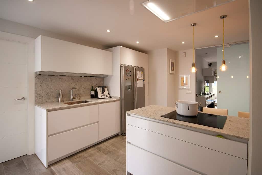 Cocina moderna en U con península de madera y armarios blancos en Tomelloso