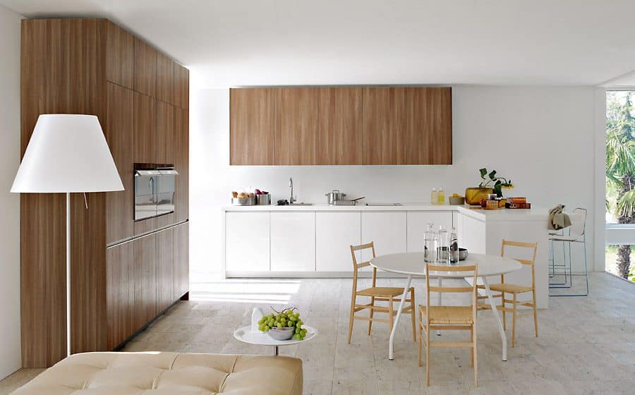 Cocina de diseño lineal blanco con armarios de madera y mesa de comedor redonda en Tomelloso