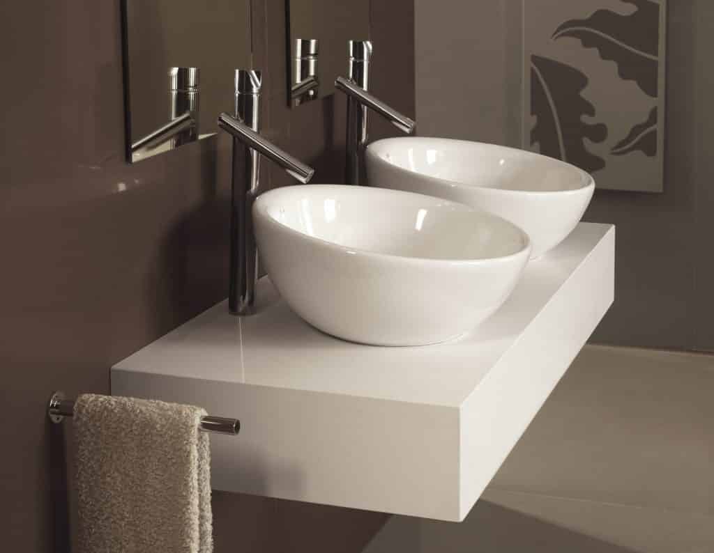 Mueble de baño moderno con encimera suspendida blanca, dos lavabos sobre encimera ovalados y grifería cromada en Tomelloso