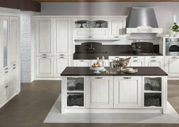 Cocina rústica blanca con isla central de encimera oscura, campana decorativa y vitrinas en Tomelloso