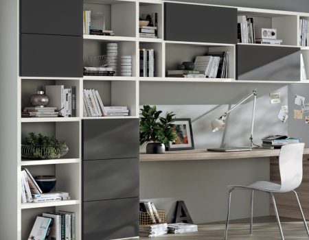 Mueble de salón modular con estanterías blancas, cajones gris oscuro y zona de escritorio con silla en Tomelloso